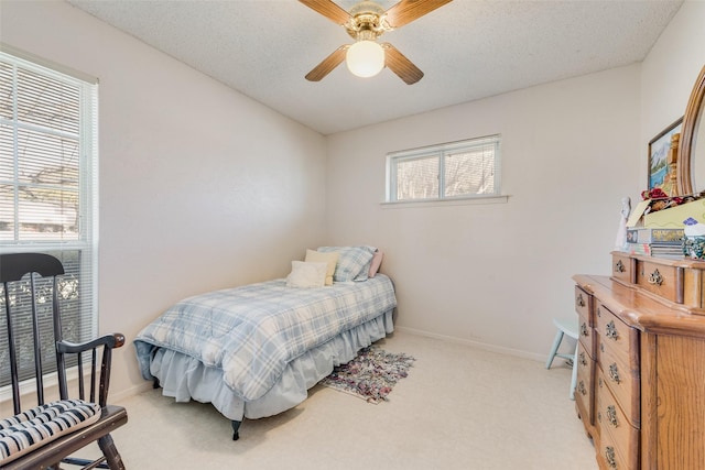 carpeted bedroom featuring multiple windows, a textured ceiling, and ceiling fan