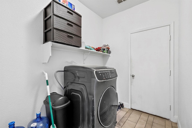 clothes washing area with washer / clothes dryer and light tile patterned floors