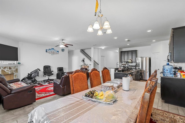 dining area featuring a stone fireplace and ceiling fan with notable chandelier