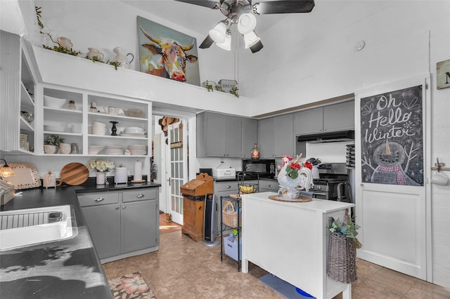 kitchen with stainless steel gas range, sink, gray cabinets, a towering ceiling, and ceiling fan