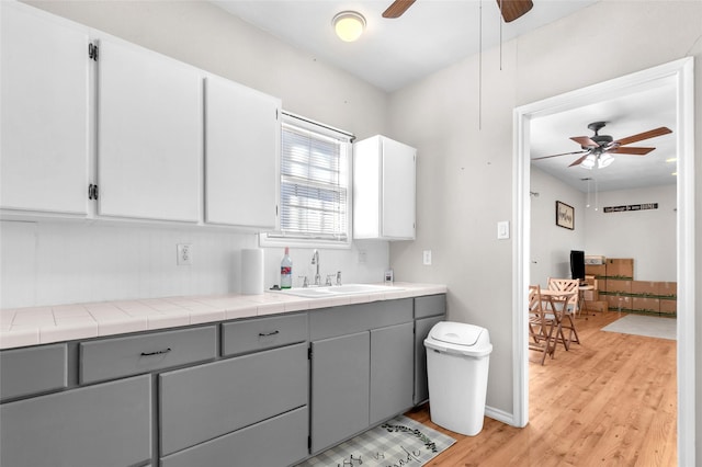 kitchen with gray cabinetry, sink, and tile counters