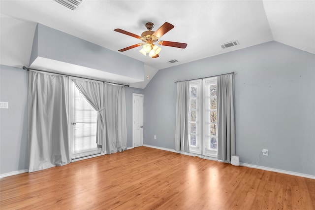 empty room featuring vaulted ceiling, a healthy amount of sunlight, and light wood-type flooring