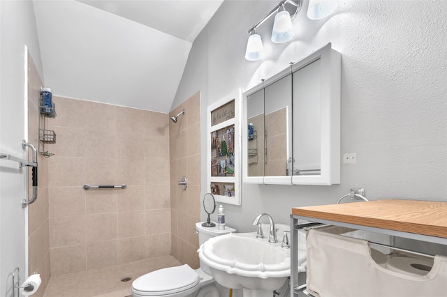 bathroom featuring sink, vaulted ceiling, toilet, and tiled shower