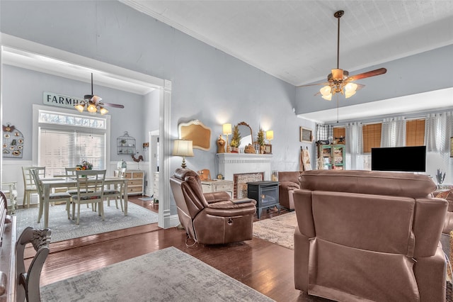 living room with lofted ceiling, dark wood-type flooring, ceiling fan, and a wood stove