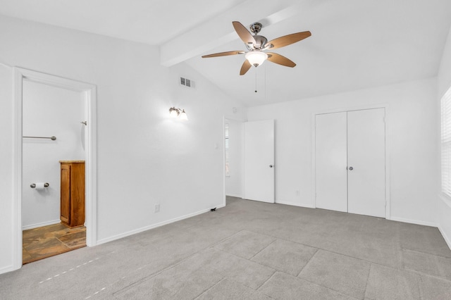 unfurnished bedroom featuring connected bathroom, vaulted ceiling with beams, ceiling fan, light carpet, and a closet