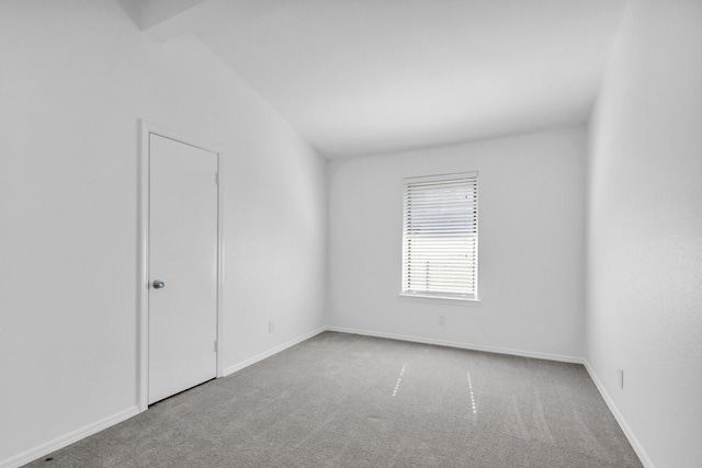 carpeted spare room with vaulted ceiling