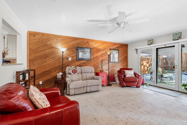 living room with crown molding, ceiling fan, and wood walls