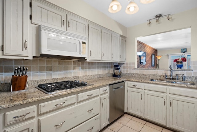 kitchen with sink, appliances with stainless steel finishes, tasteful backsplash, light stone countertops, and light tile patterned flooring