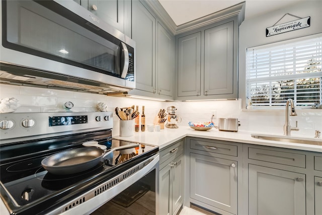 kitchen featuring stainless steel appliances, sink, backsplash, and gray cabinets