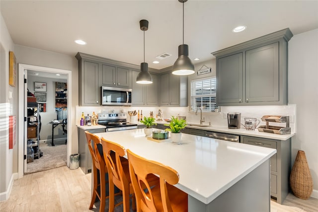 kitchen featuring stainless steel appliances, a kitchen island, gray cabinets, and sink