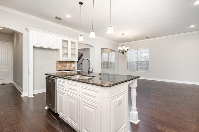 kitchen with arched walkways, dishwasher, an island with sink, glass insert cabinets, and a sink