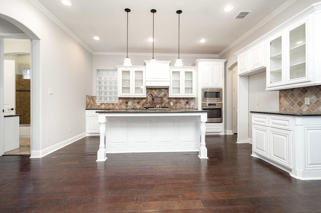 kitchen with visible vents, arched walkways, dark countertops, glass insert cabinets, and stainless steel appliances