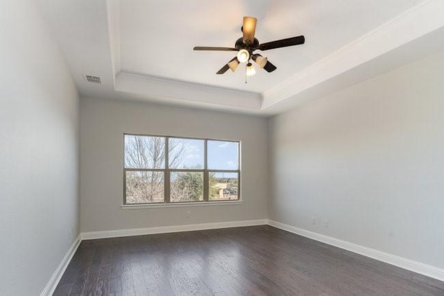 spare room with a tray ceiling, ornamental molding, dark hardwood / wood-style floors, and ceiling fan