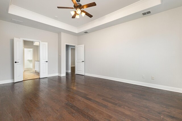 unfurnished bedroom featuring baseboards, visible vents, a tray ceiling, and dark wood-style flooring