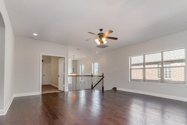 empty room featuring dark hardwood / wood-style flooring, a wealth of natural light, and ceiling fan