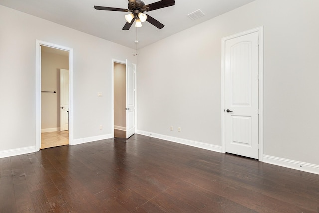 spare room featuring ceiling fan, dark wood-style flooring, visible vents, and baseboards