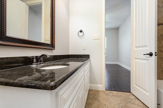 bathroom with tile patterned floors, a washtub, baseboards, and vanity