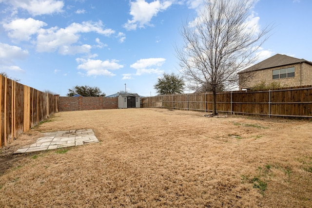 view of yard featuring a fenced backyard, a storage unit, and an outdoor structure