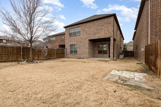 rear view of house featuring brick siding, a fenced backyard, and a patio