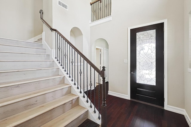 foyer featuring dark hardwood / wood-style flooring, a towering ceiling, and a wealth of natural light