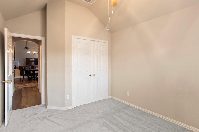 unfurnished bedroom with vaulted ceiling, carpet, ceiling fan, and a closet