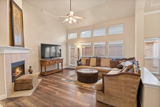 living room with ceiling fan, high vaulted ceiling, a tiled fireplace, and hardwood / wood-style floors