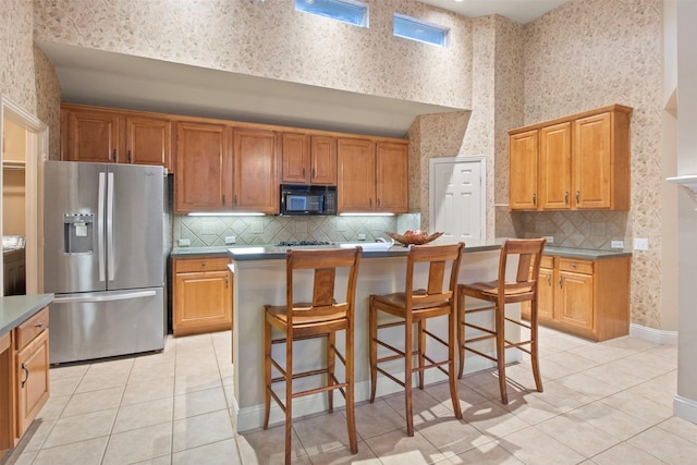 kitchen featuring stainless steel refrigerator with ice dispenser, a breakfast bar area, light tile patterned flooring, and a kitchen island