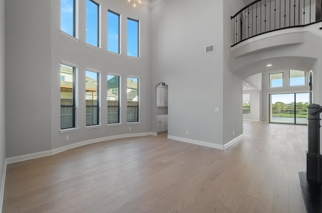 unfurnished living room with a towering ceiling and light hardwood / wood-style flooring