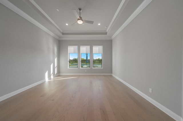 unfurnished room featuring a tray ceiling, light hardwood / wood-style flooring, ornamental molding, and ceiling fan