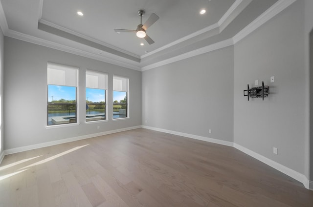 unfurnished room with ceiling fan, ornamental molding, a tray ceiling, and wood-type flooring