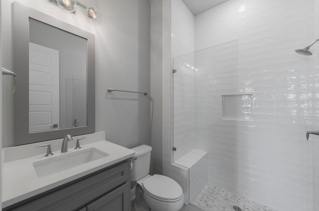 bathroom with vanity, toilet, and a tile shower