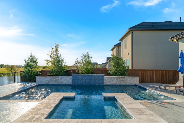 view of pool with an in ground hot tub, a water view, and a patio area