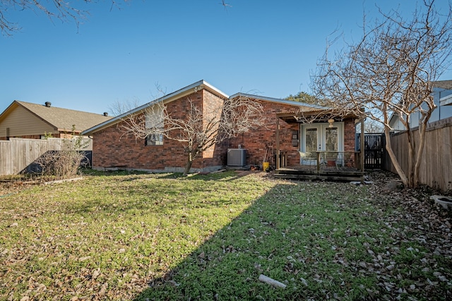 rear view of house featuring french doors, a fenced backyard, a yard, and brick siding