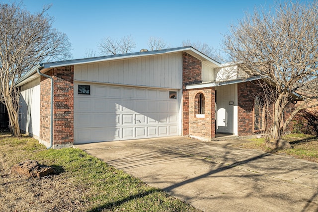 view of side of property featuring brick siding, an attached garage, and concrete driveway