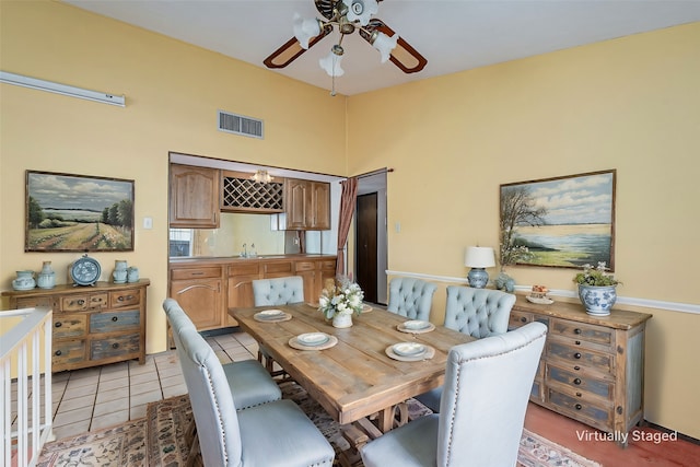 dining space featuring a towering ceiling, light tile patterned floors, visible vents, and ceiling fan
