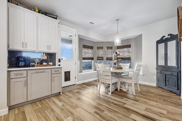 kitchen featuring hanging light fixtures, white cabinetry, tasteful backsplash, and light hardwood / wood-style floors