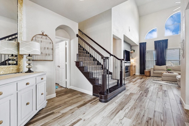 entryway featuring a towering ceiling and light wood-type flooring