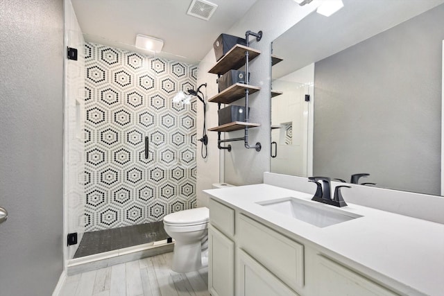 bathroom featuring vanity, toilet, and a shower with door