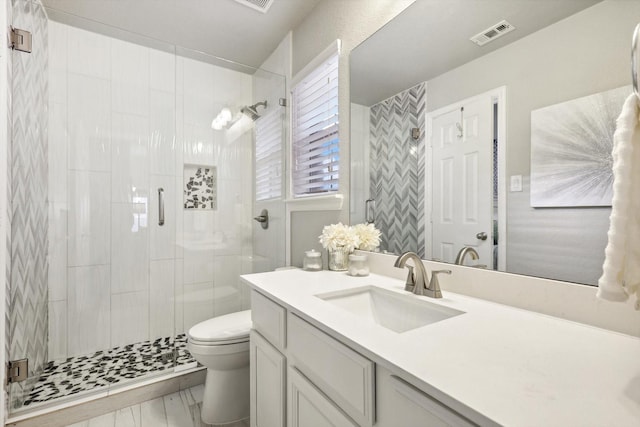 bathroom featuring vanity, toilet, and a shower with door