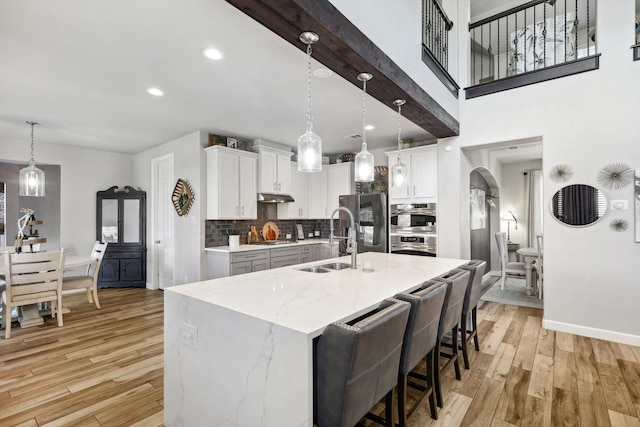 kitchen featuring white cabinetry, decorative light fixtures, sink, and light hardwood / wood-style flooring