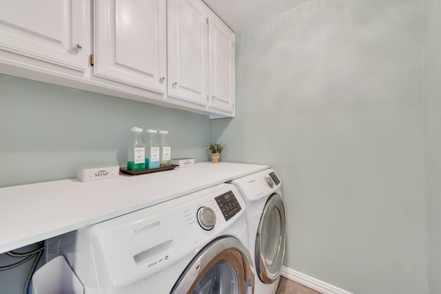 clothes washing area with cabinets and washer and dryer