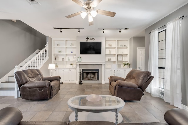 tiled living room with ceiling fan and a tiled fireplace