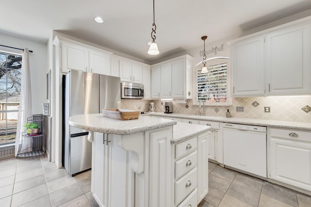 kitchen featuring light tile patterned floors, white cabinetry, stainless steel appliances, a center island, and decorative light fixtures