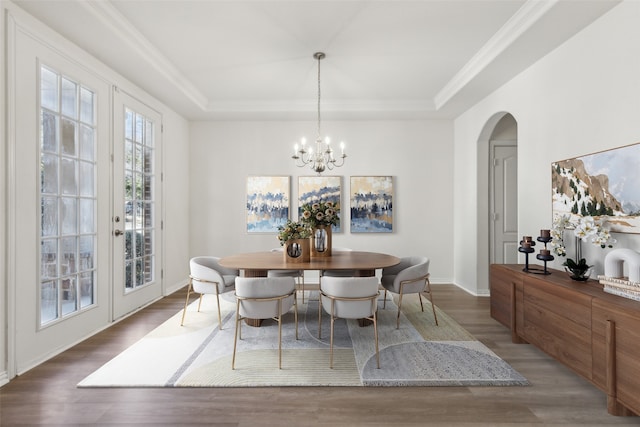 dining space with dark wood-type flooring, a raised ceiling, french doors, and a notable chandelier