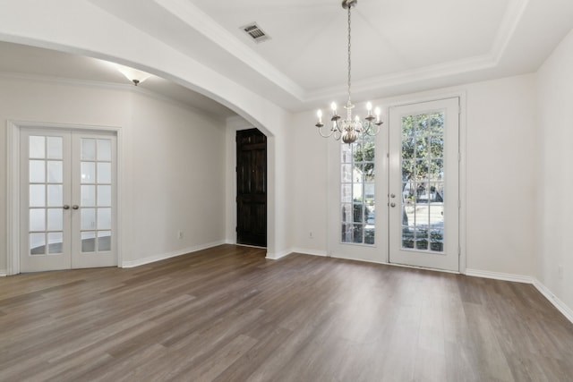 spare room featuring an inviting chandelier, hardwood / wood-style floors, french doors, and a raised ceiling