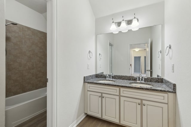 bathroom with wood-type flooring, tiled shower / bath combo, and vanity