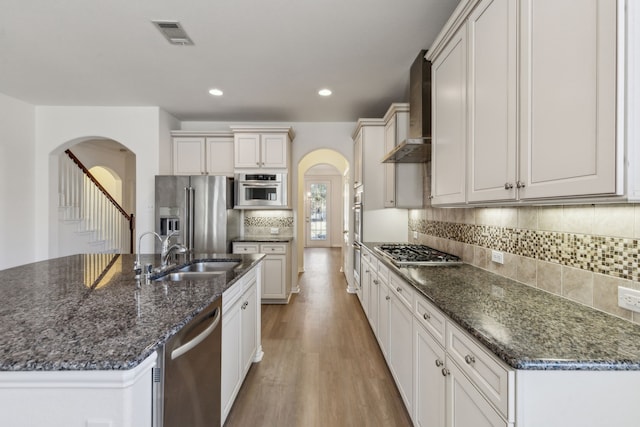 kitchen with stainless steel appliances, sink, white cabinets, and wall chimney exhaust hood