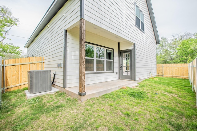 rear view of property with cooling unit, a patio area, and a lawn