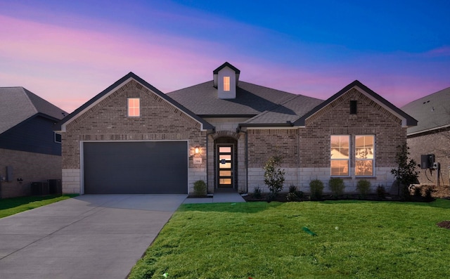 view of front of property featuring a front yard, cooling unit, a shingled roof, concrete driveway, and brick siding