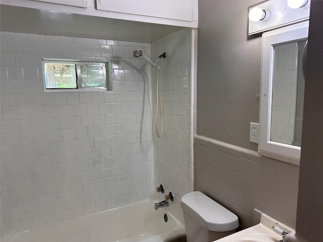1234 N Travis St, Sherman, TX 75092 - bathroom featuring toilet, shower / washtub combination, tile walls, a wainscoted wall, and a sink